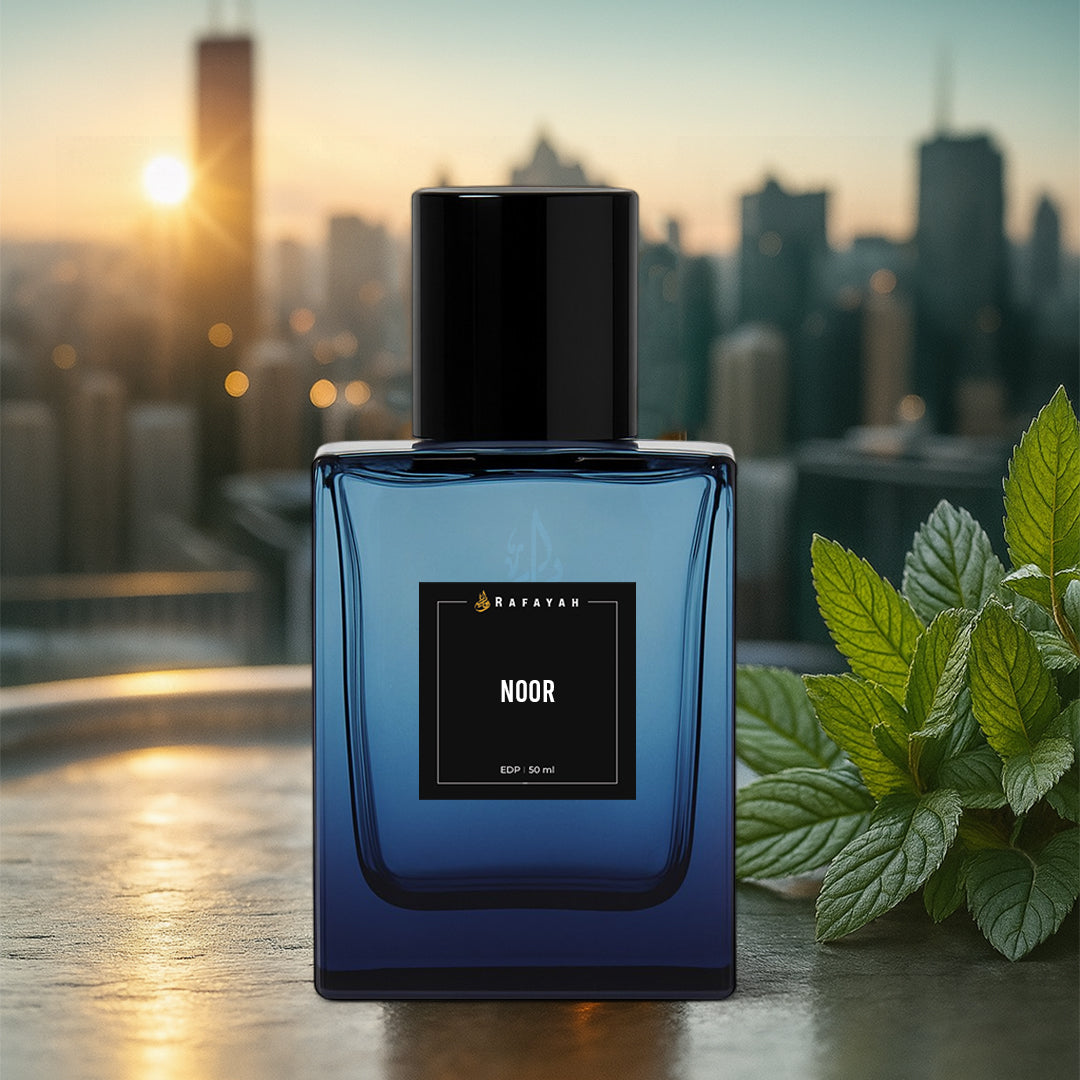 Noor perfume bottle on a city rooftop at sunset with green mint leaves nearby